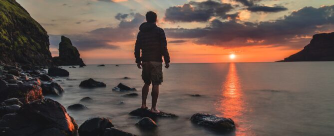 Man thinks about creativity looking at a sunset.